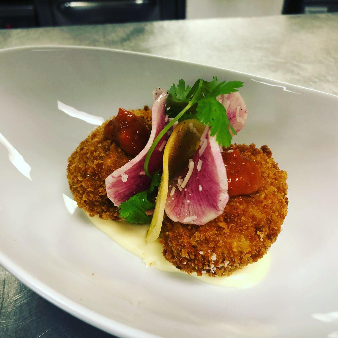 A white plate displaying a crispy fried fish cake, perfectly cooked and presented for enjoyment.