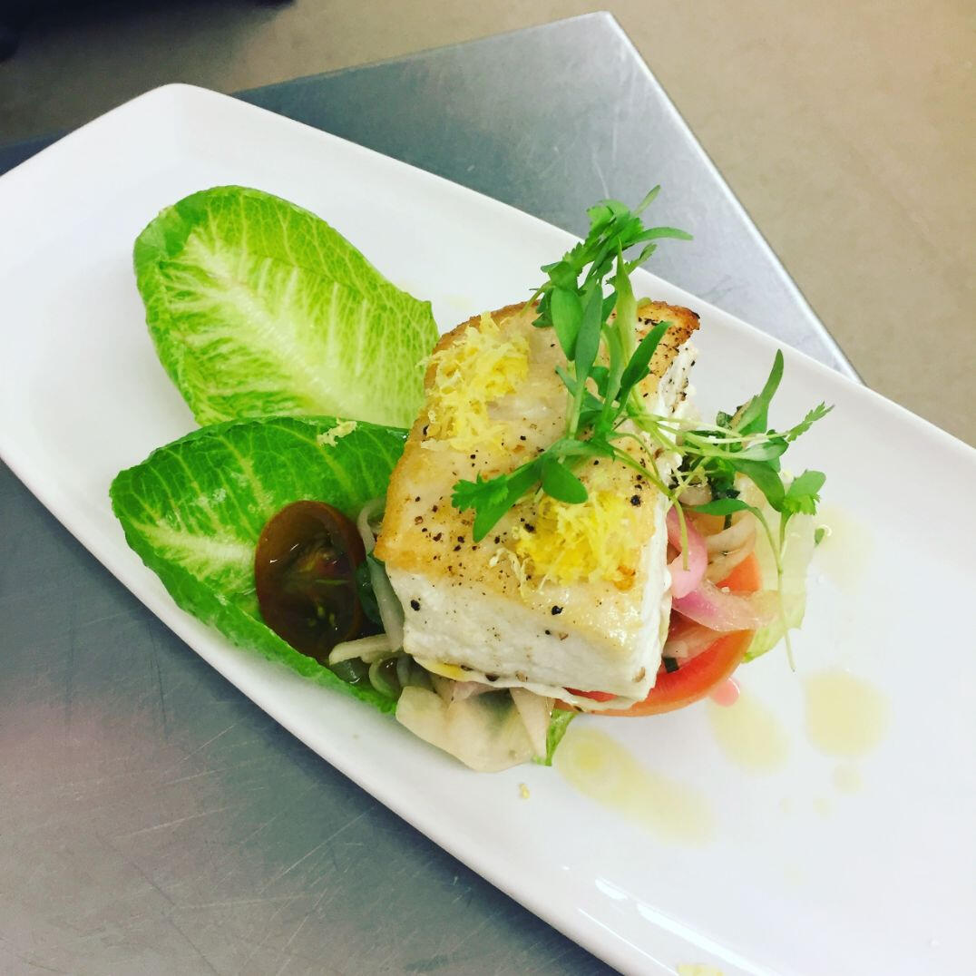 A pristine white plate featuring a delectable fish dish, artfully arranged for an appealing presentation.