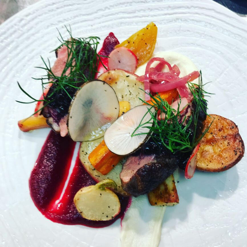 A beautifully presented plate containing meat, vibrant vegetables, and a flavorful sauce, ready to be enjoyed.