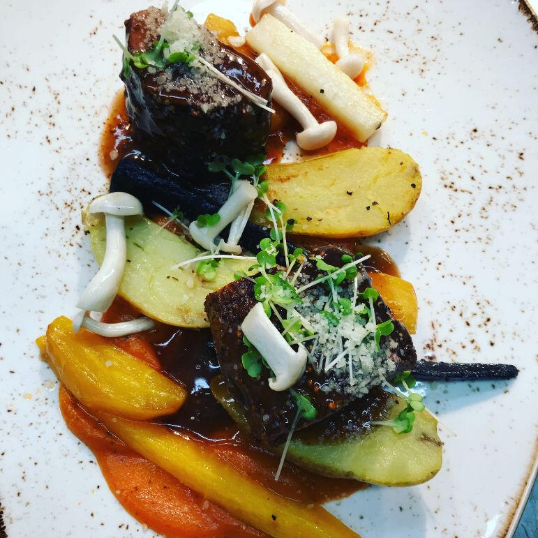 A plate featuring a serving of meat accompanied by potatoes and a variety of colorful vegetables.