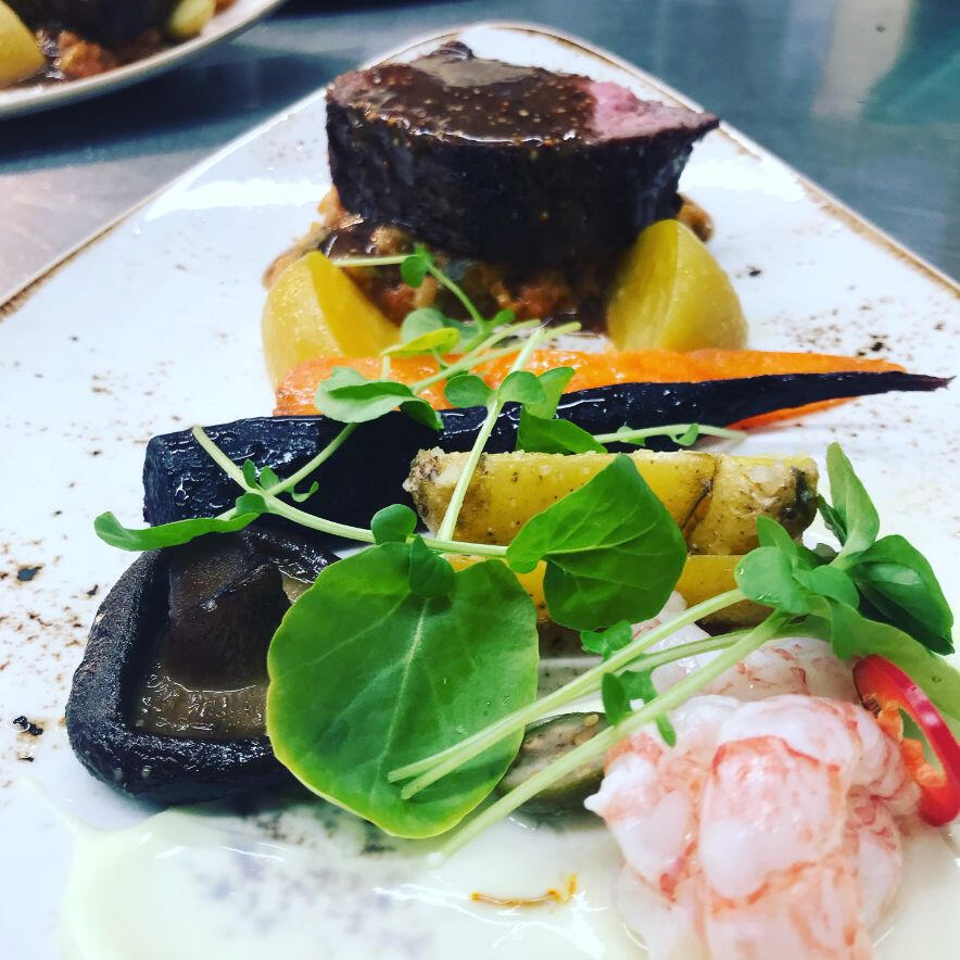 A beautifully arranged plate containing meat, vibrant vegetables, and a flavorful sauce, showcasing a delightful meal.